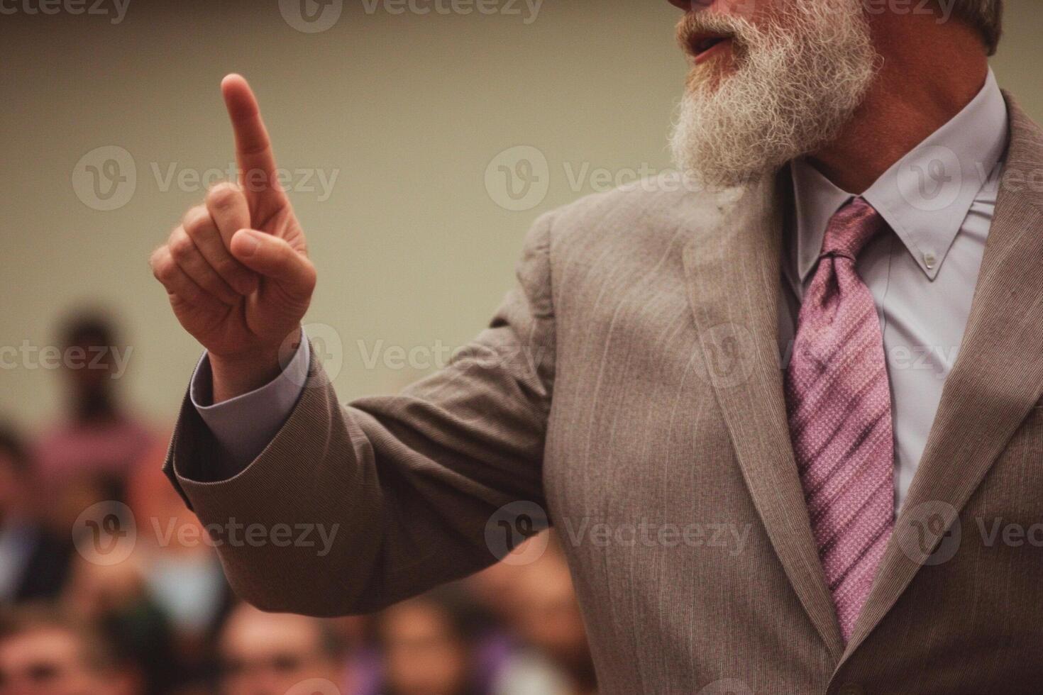 A man with a beard and a tie pointing at something photo