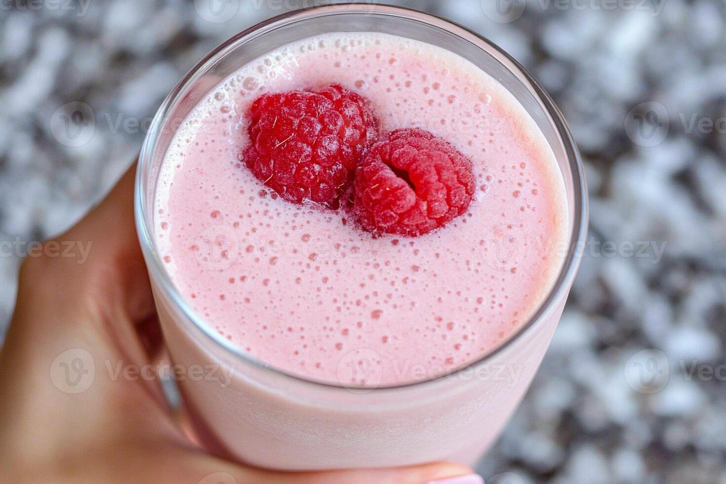 A person holding a glass of raspberry smoothie photo