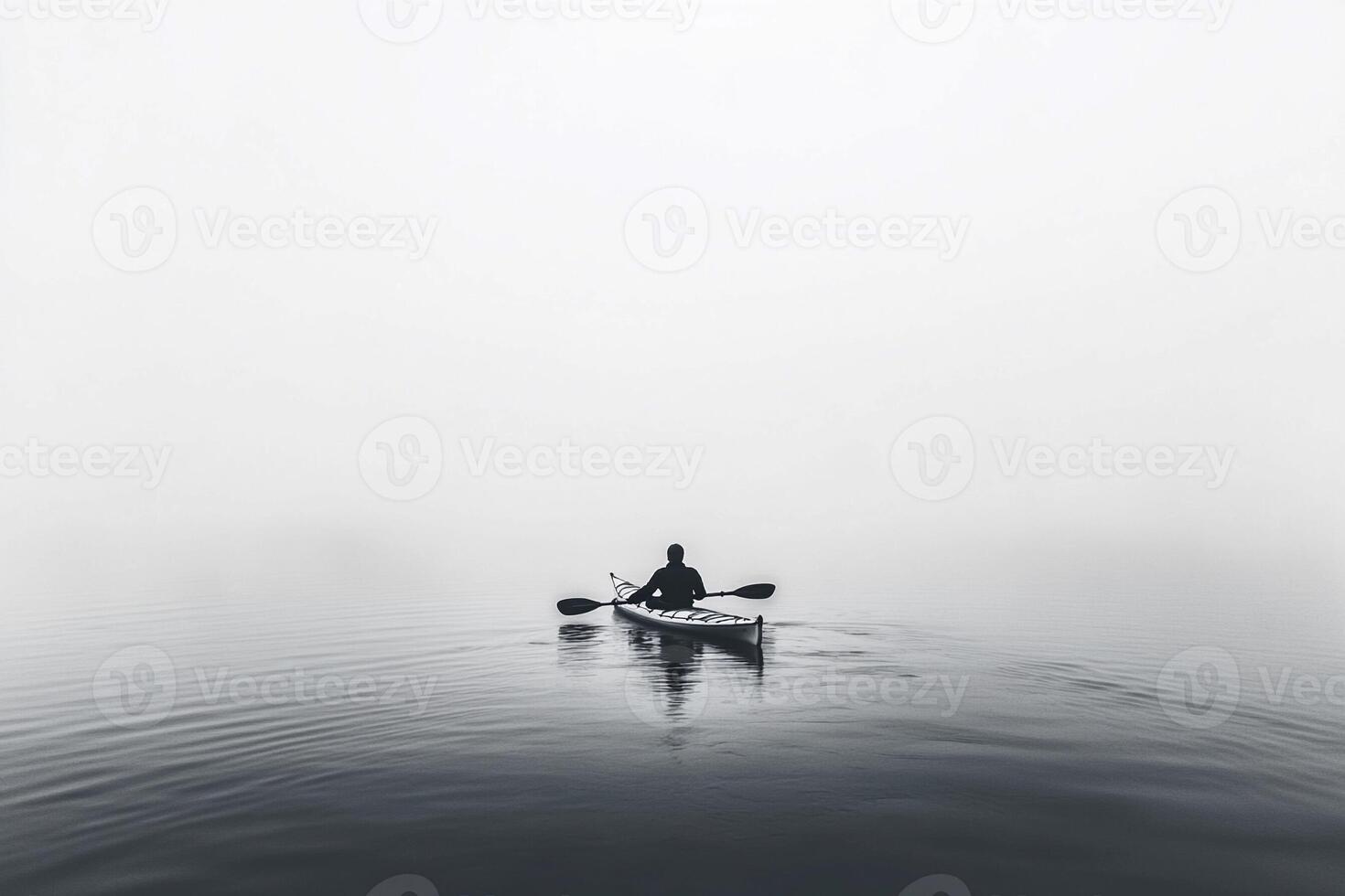 A person in a kayak on a foggy lake photo
