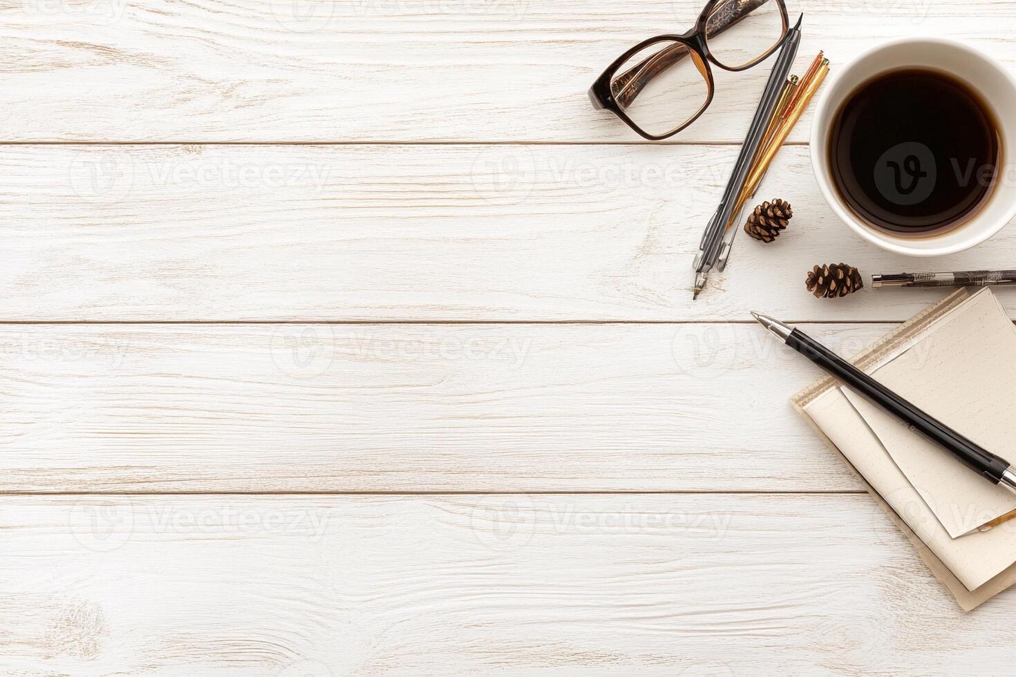 A cup of coffee, pen, notepad, and glasses on a wooden table photo