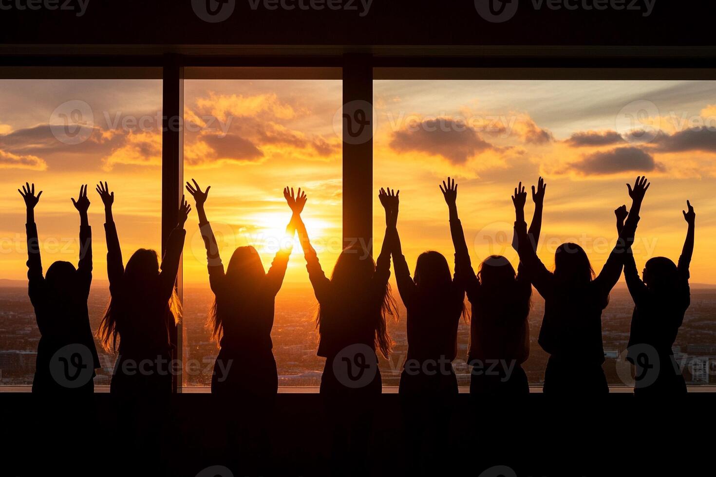Silhouette of a group of people raising their hands in the air at sunset photo