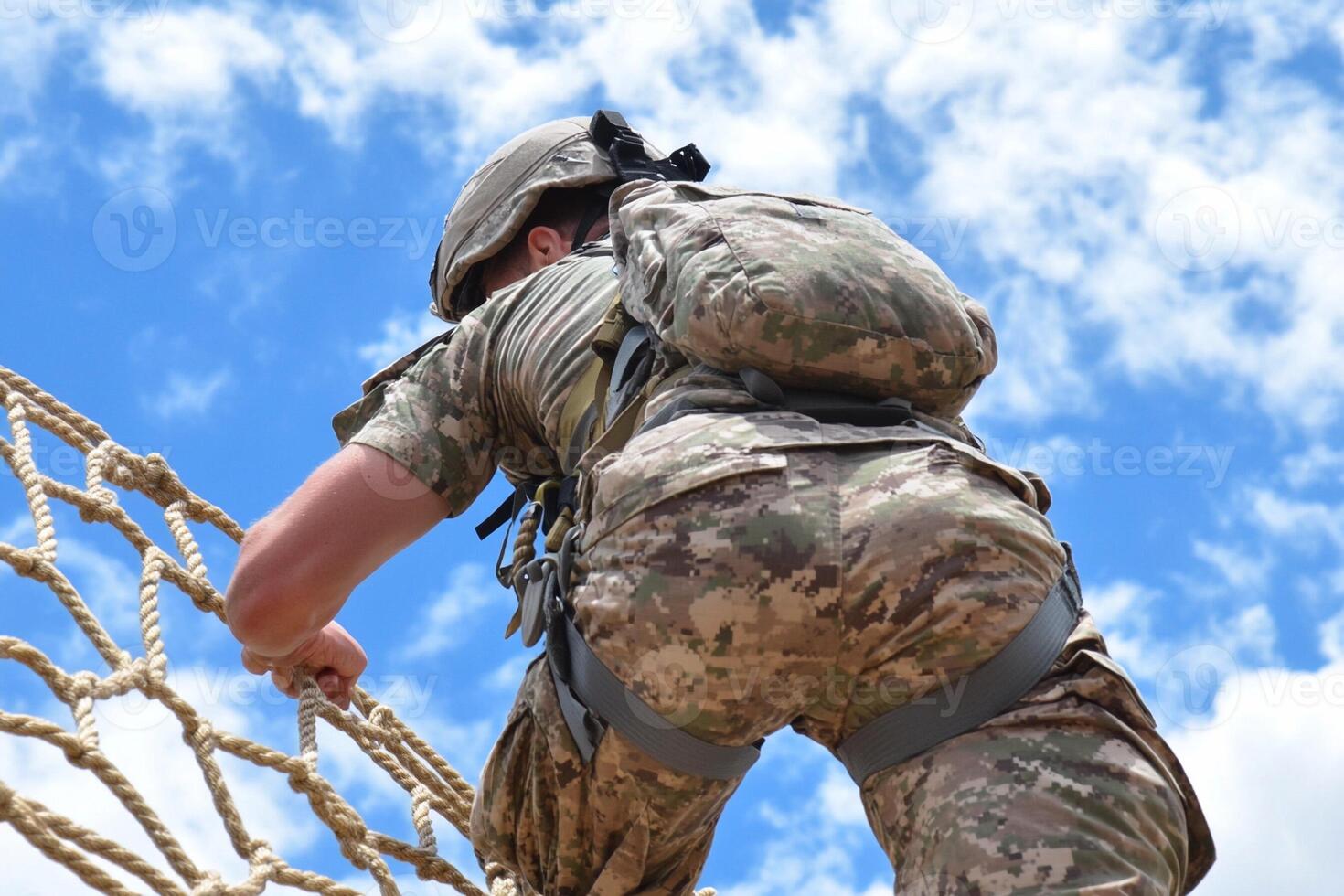 A soldier climbing over a rope net photo
