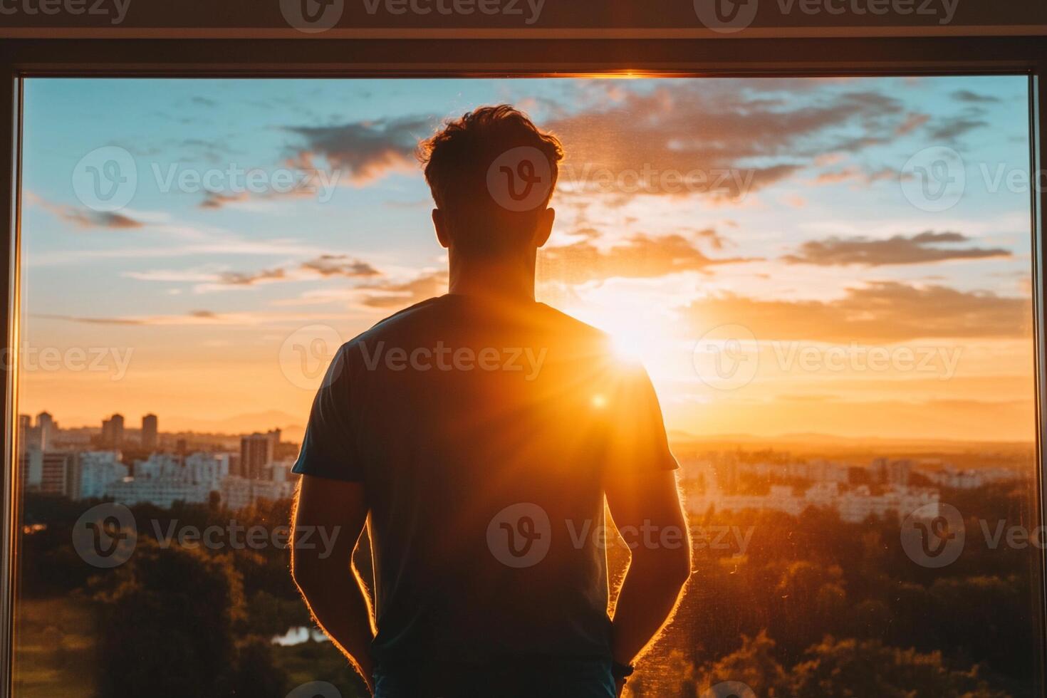 Man looking out the window at sunset photo