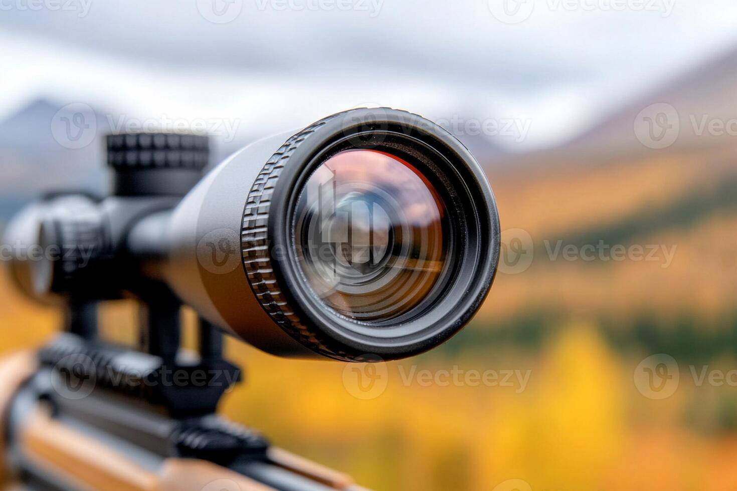 A rifle scope is on a mountain with a view of the fall foliage photo