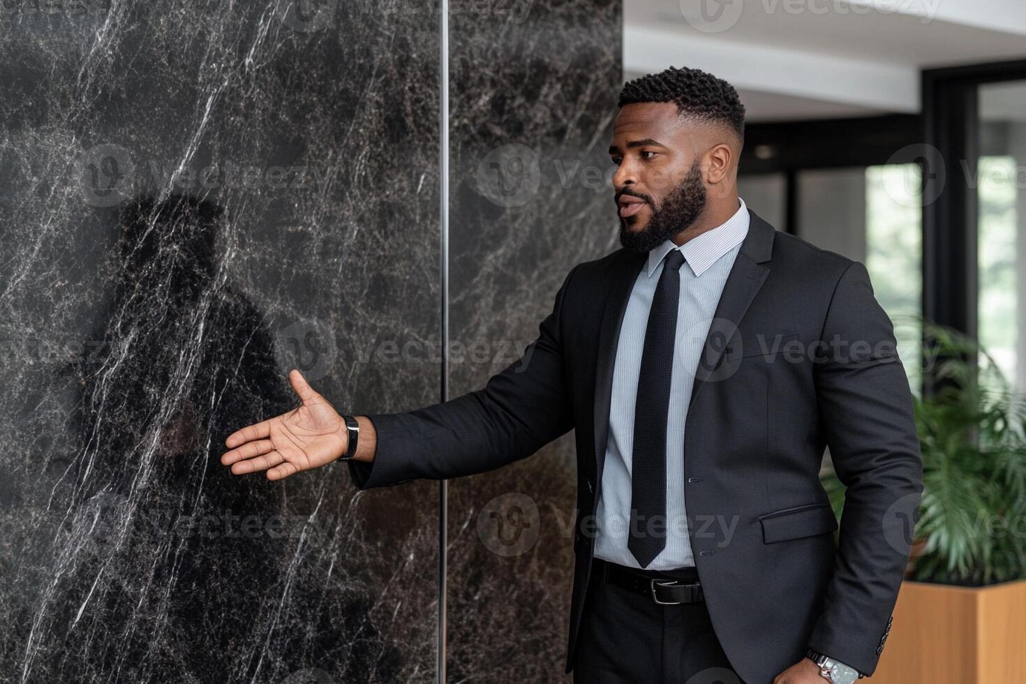 A man in a suit is standing in front of a wall photo