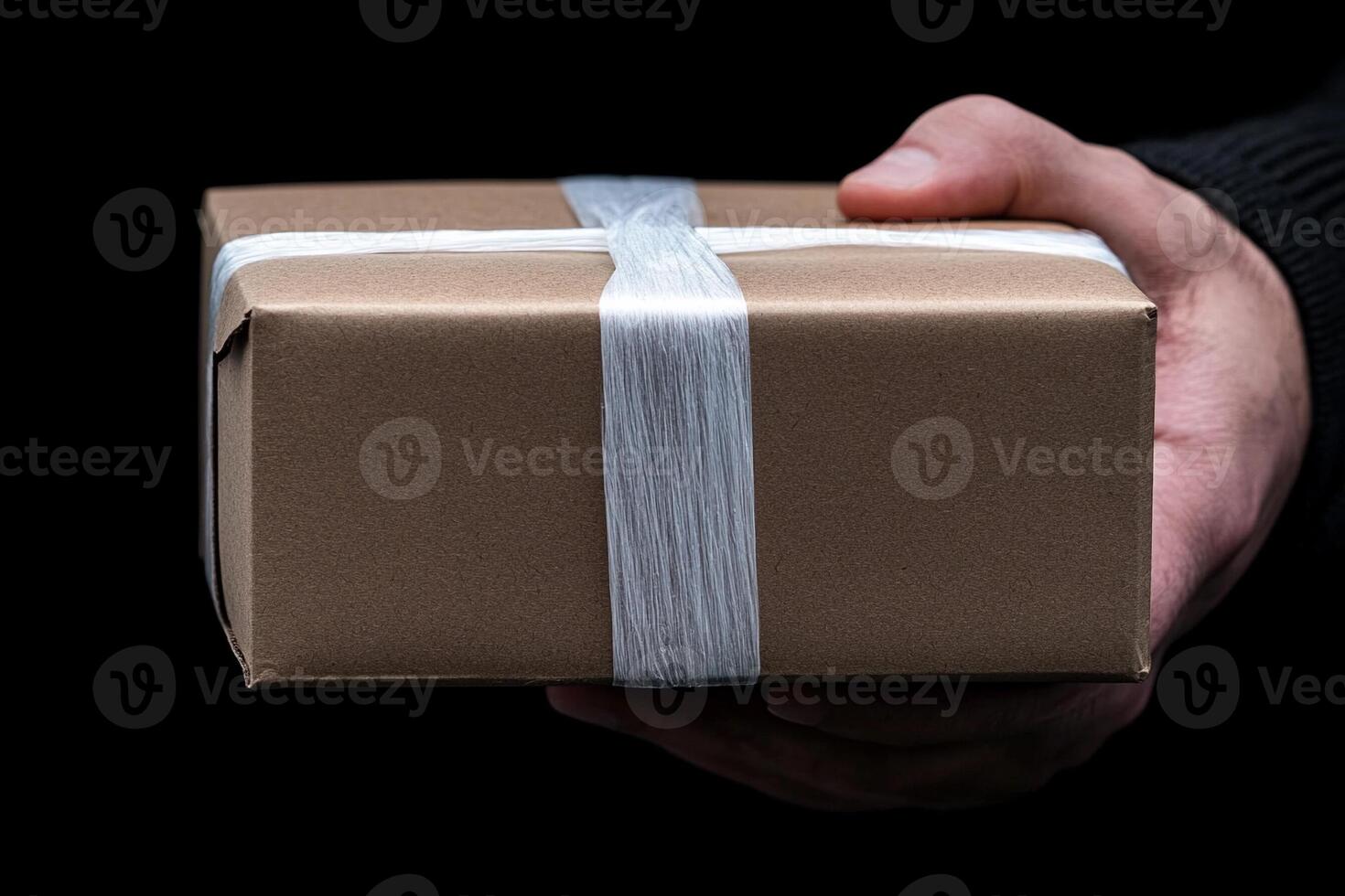 A person holding a brown box with a white ribbon photo