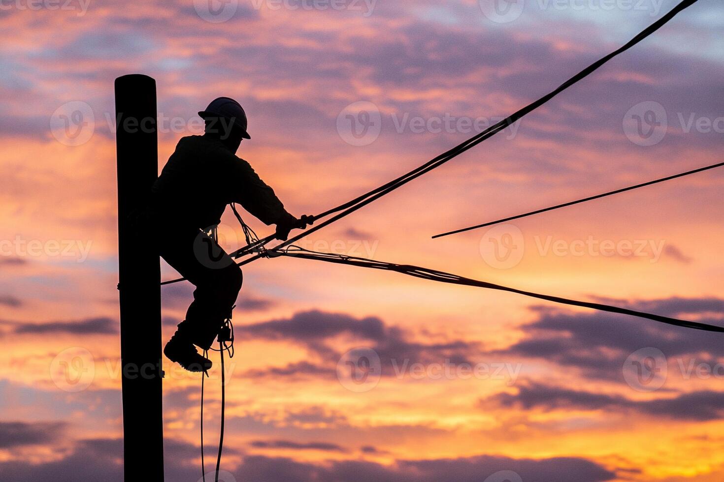 A man is working on a power pole at sunset photo