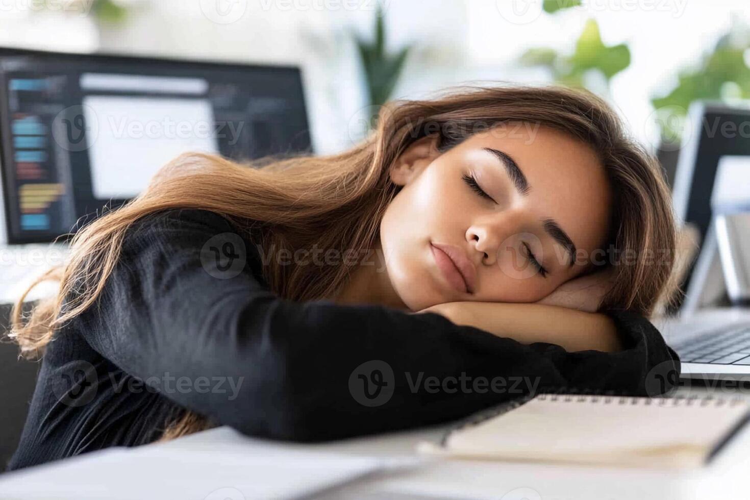 A woman sleeping on her laptop at her desk photo