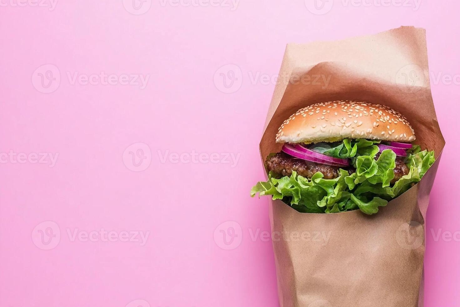 Burger in paper bag on pink background photo