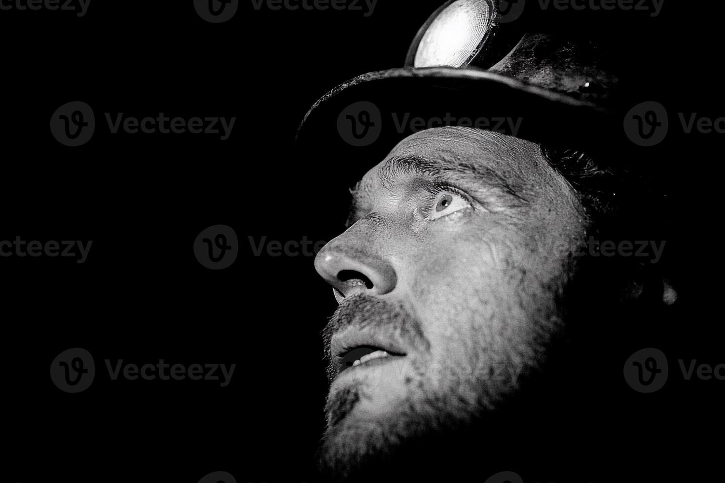 A black and white photo of a man with a light on his face