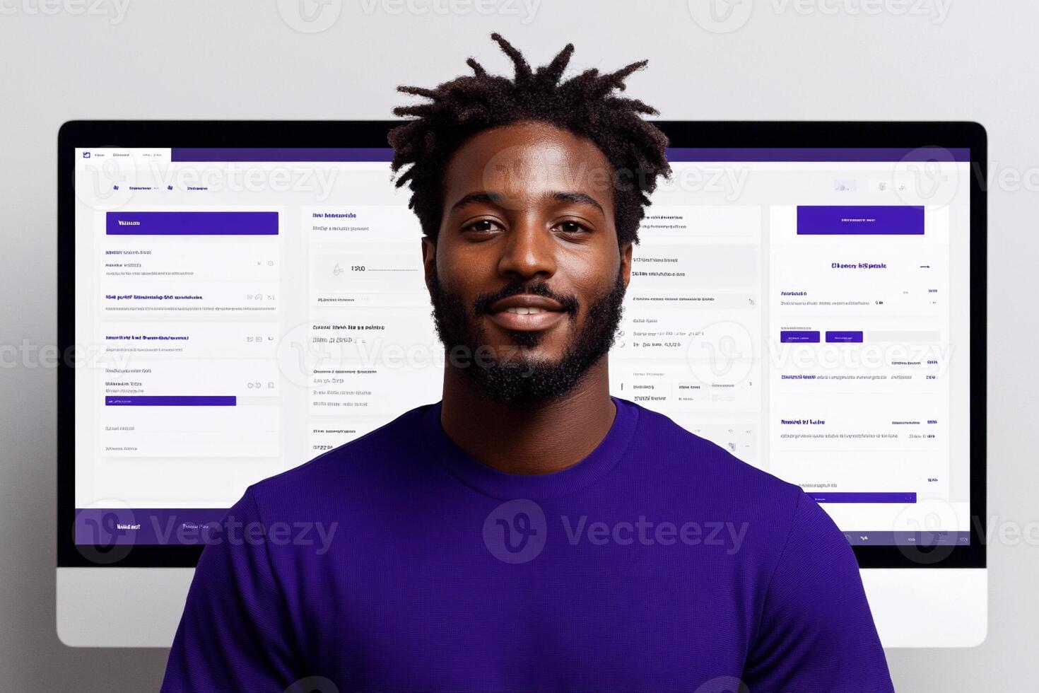 A man in purple shirt standing in front of a computer screen photo
