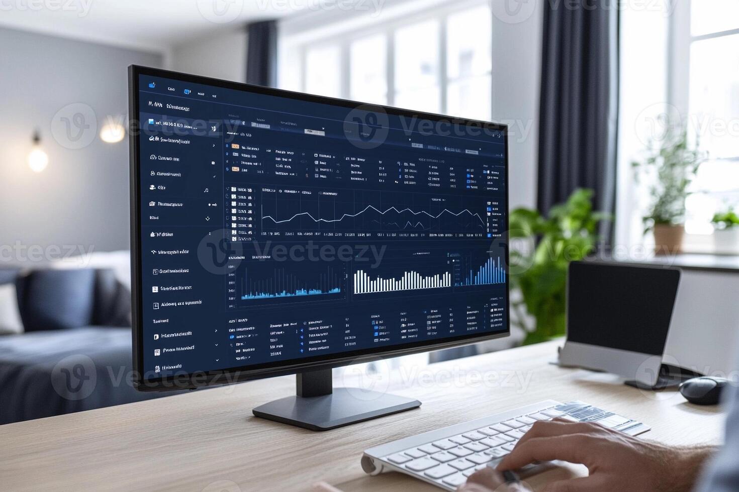 A person is sitting at a desk with a computer screen showing graphs photo