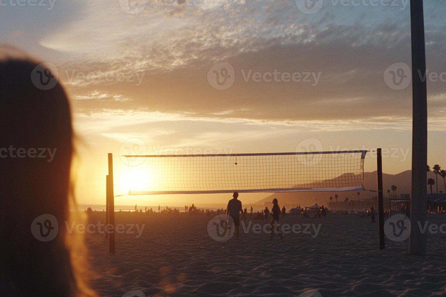 A woman is standing on the beach with a volleyball net photo