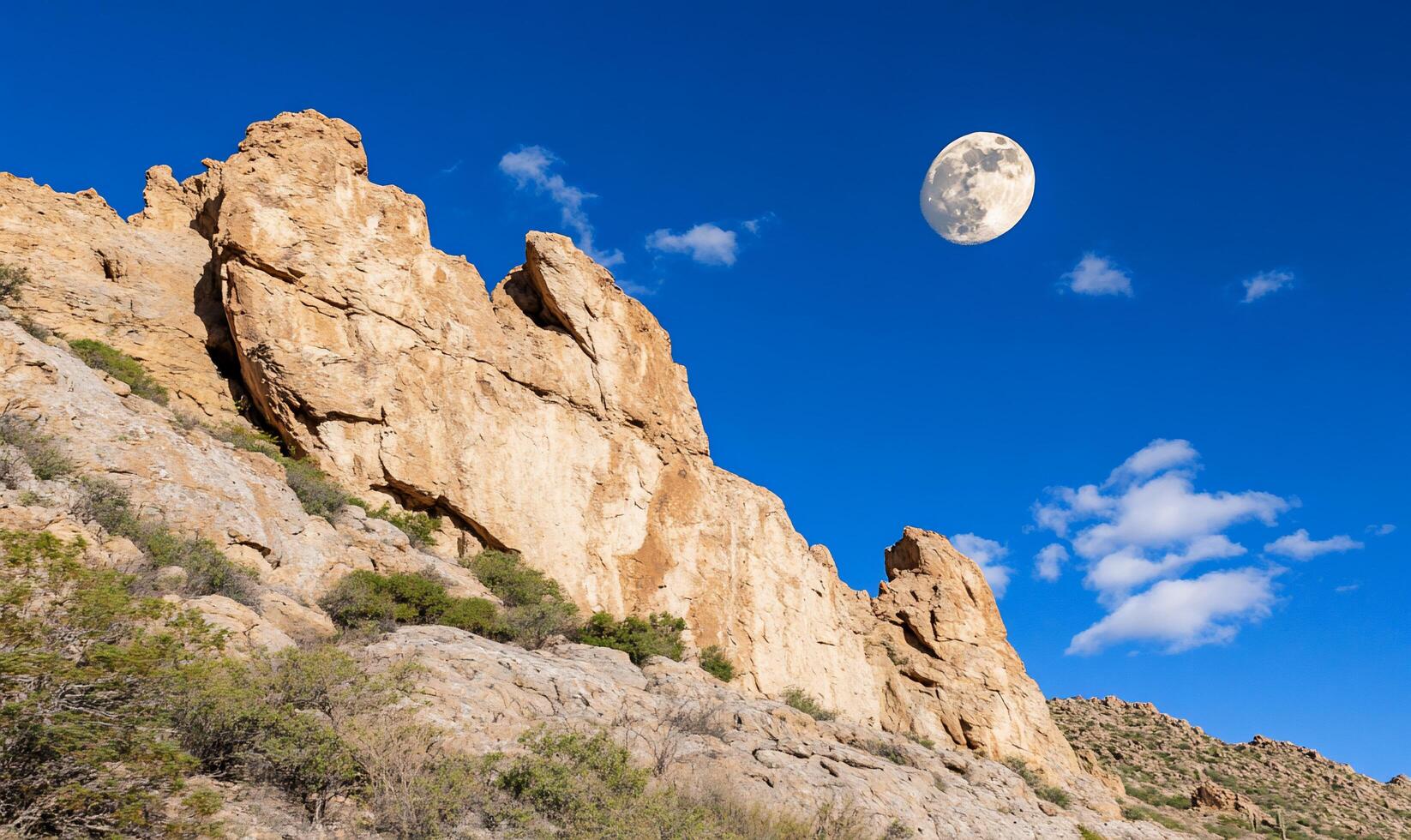 Scenic landscape featuring cliffs and a large moon in a blue sky. photo