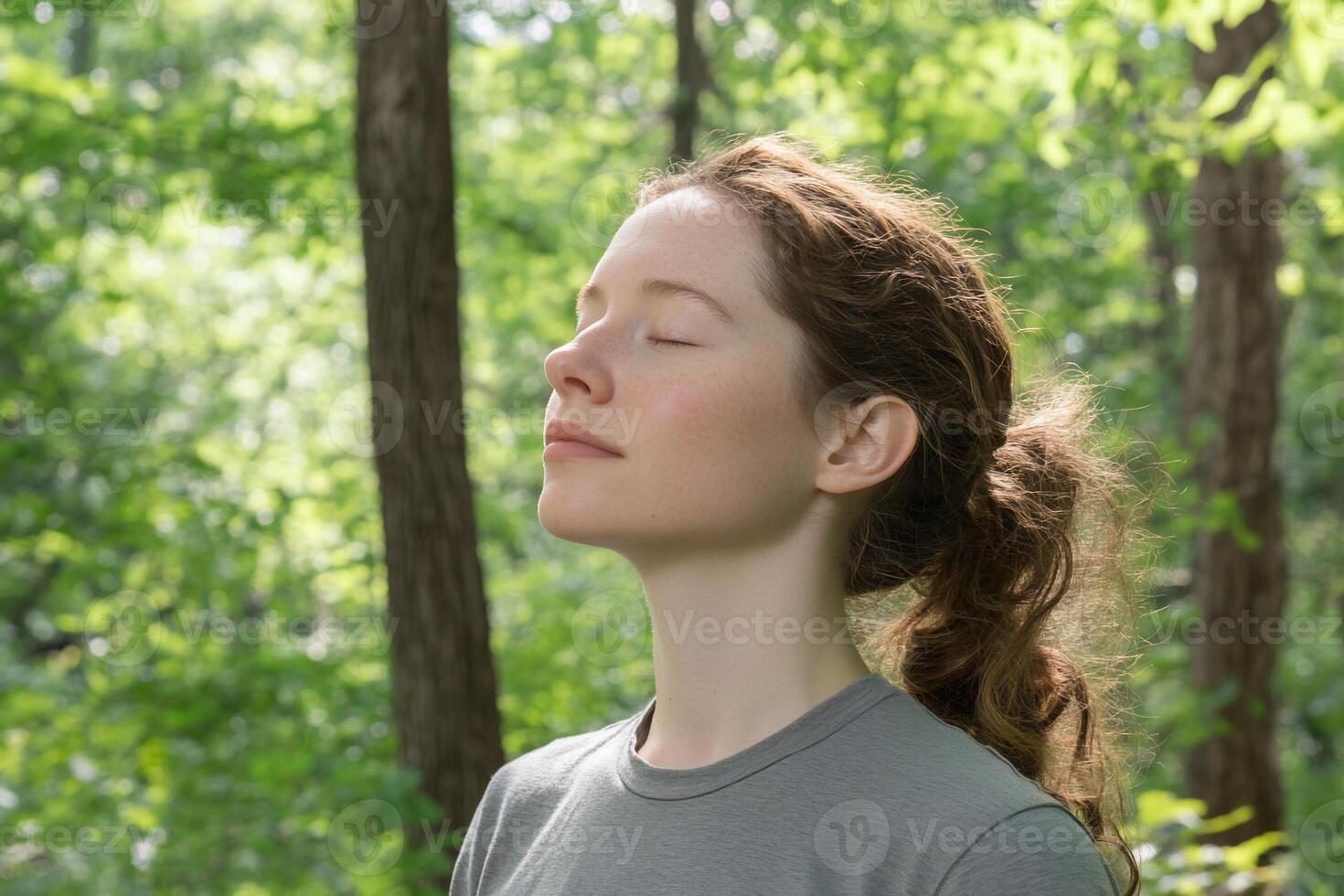 A woman in a gray shirt is looking up at the sky photo