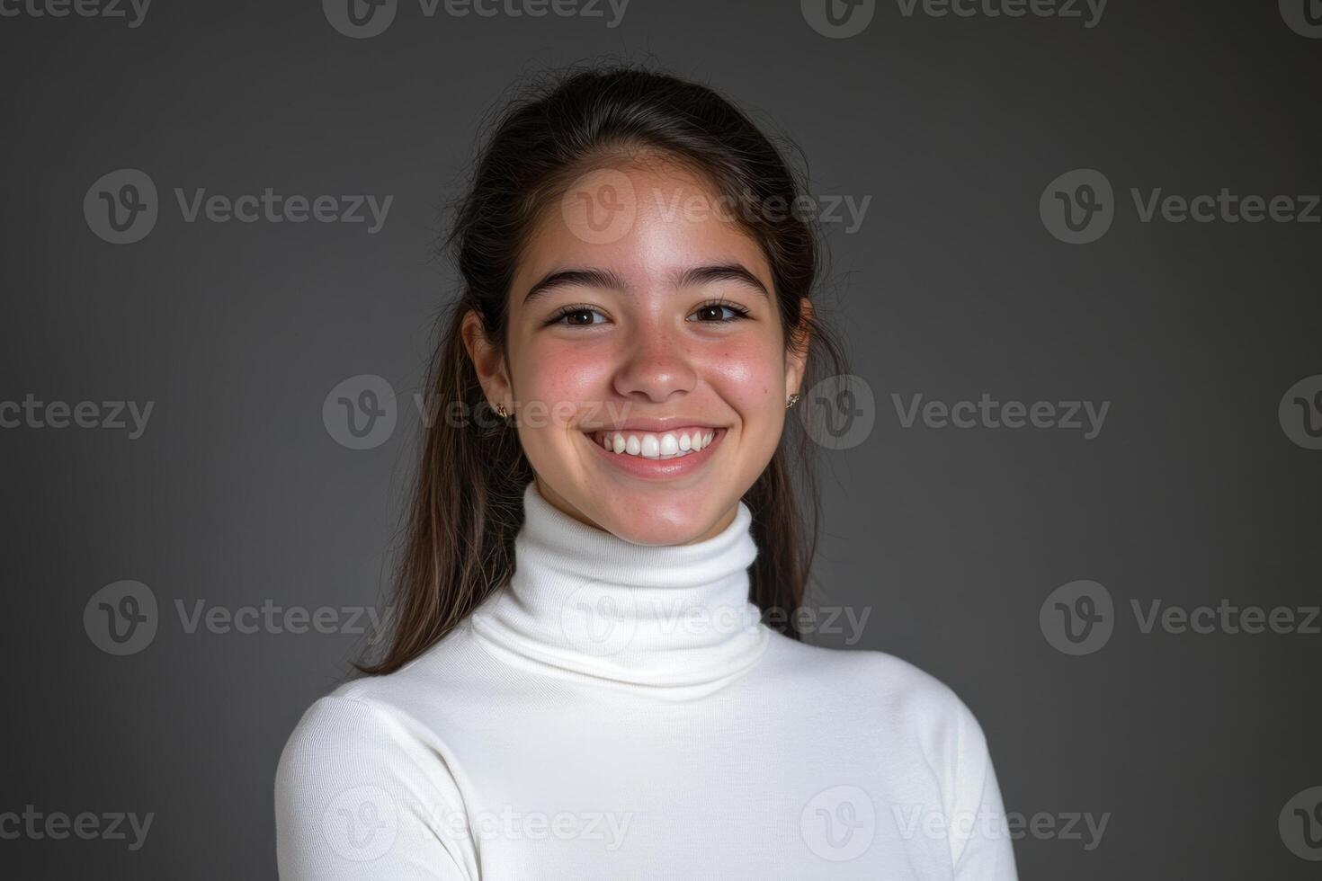 Cheerful girl smiles at the camera in a studio with a gray blurred background photo