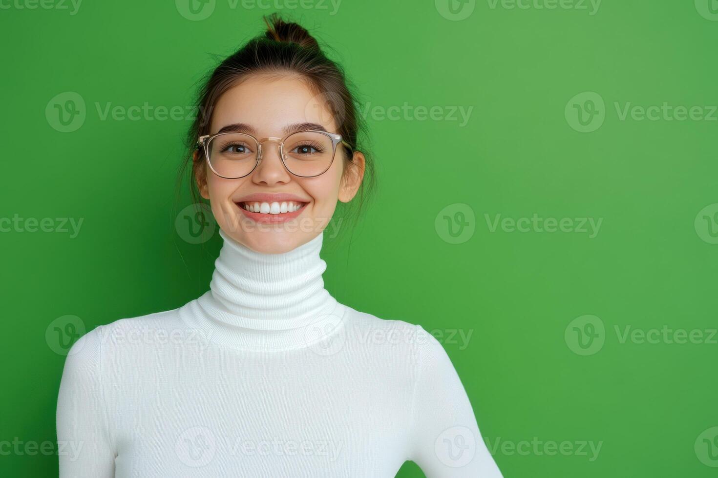 Portrait of smiling young woman wearing glasses and white turtle neck over green background photo