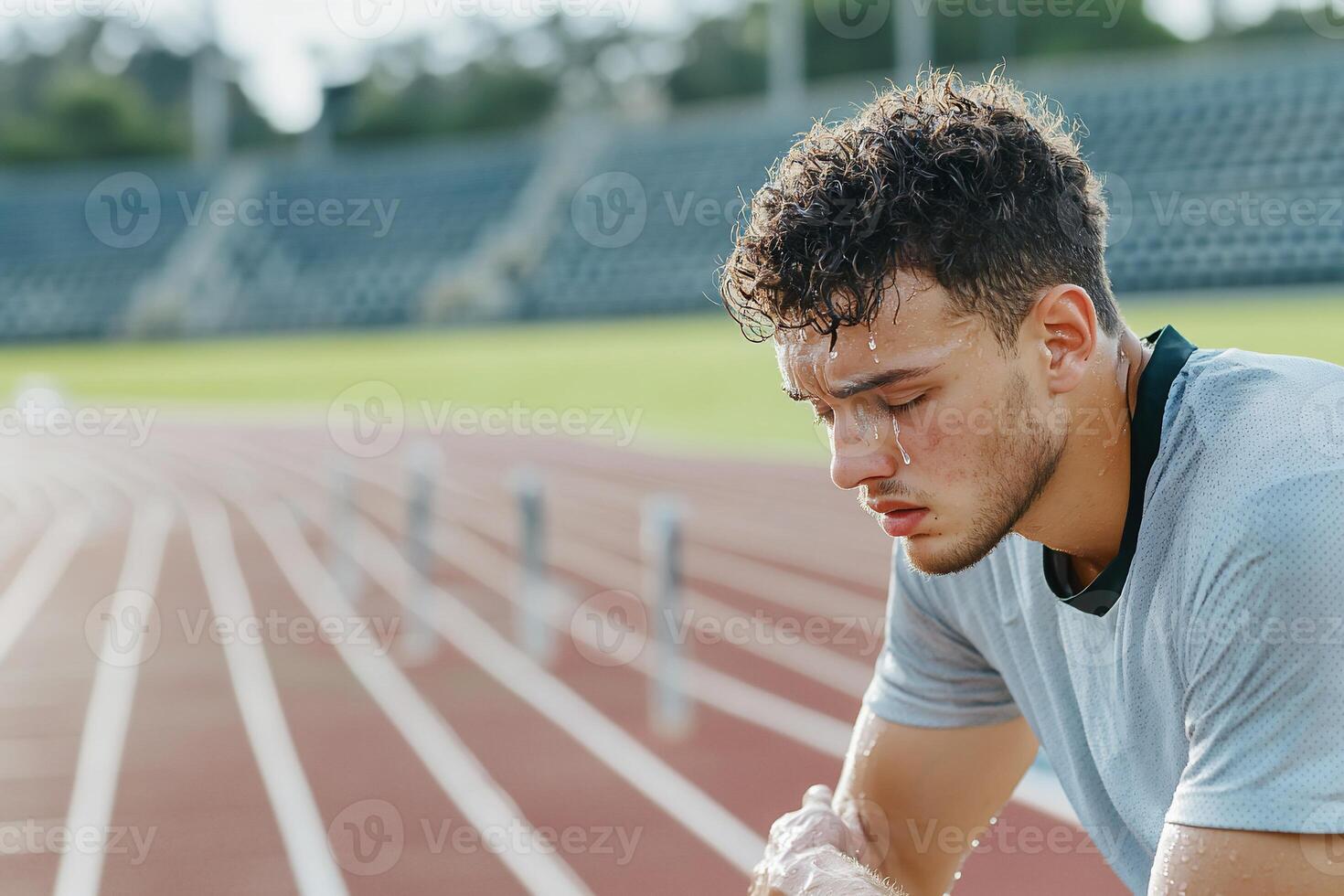 A man sitting on a running track with his head down photo
