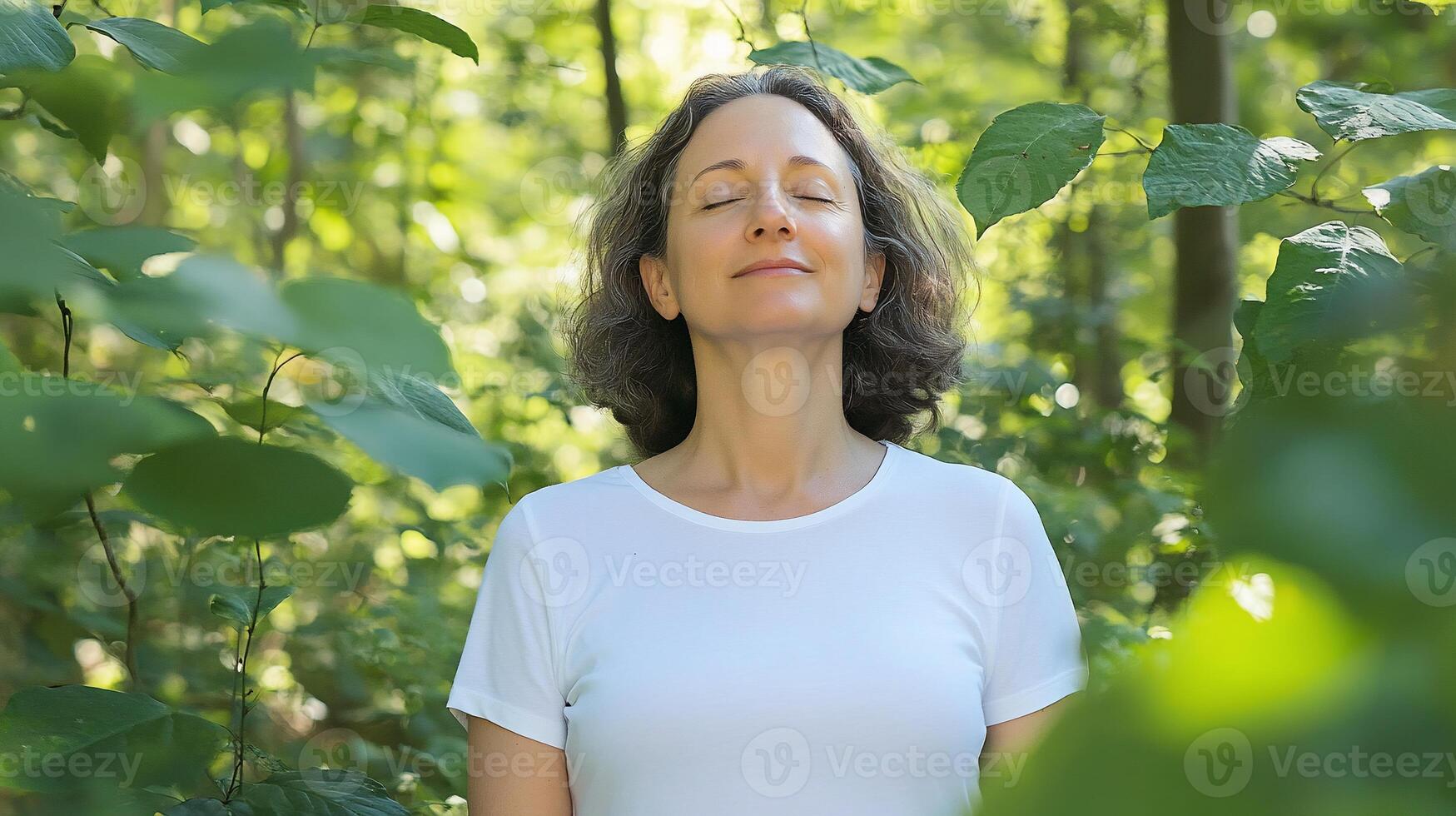 A woman in a white shirt is meditating in the woods photo
