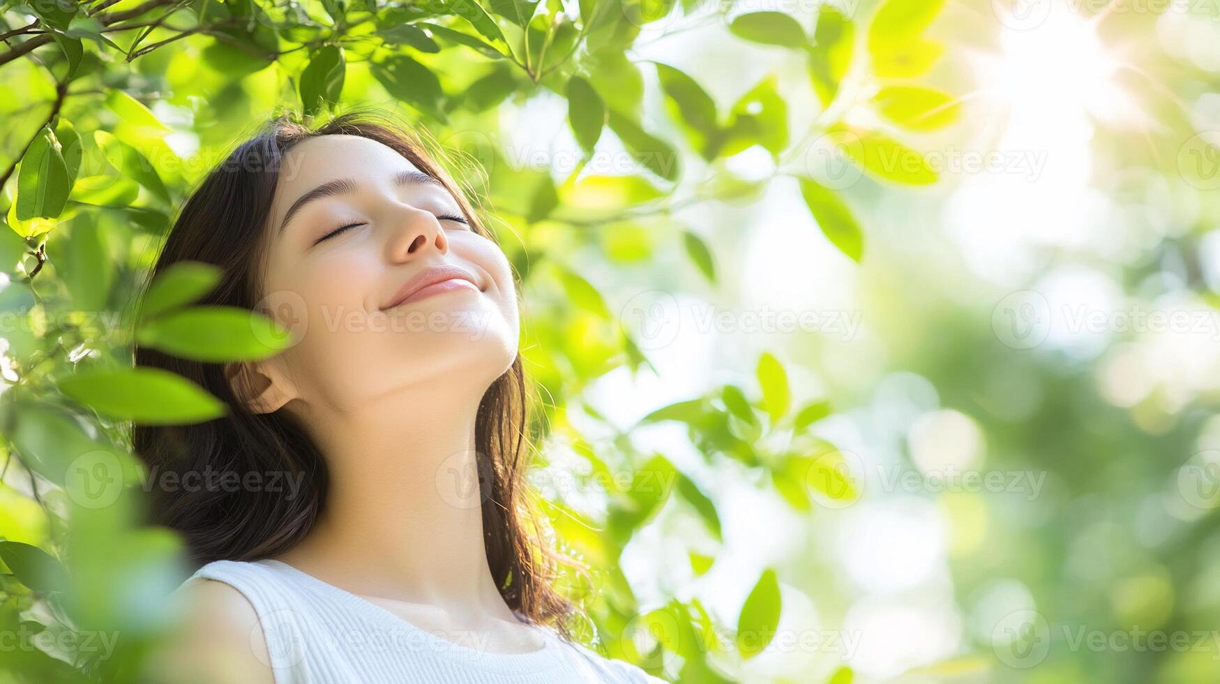 A woman is smiling while looking up at the sun photo