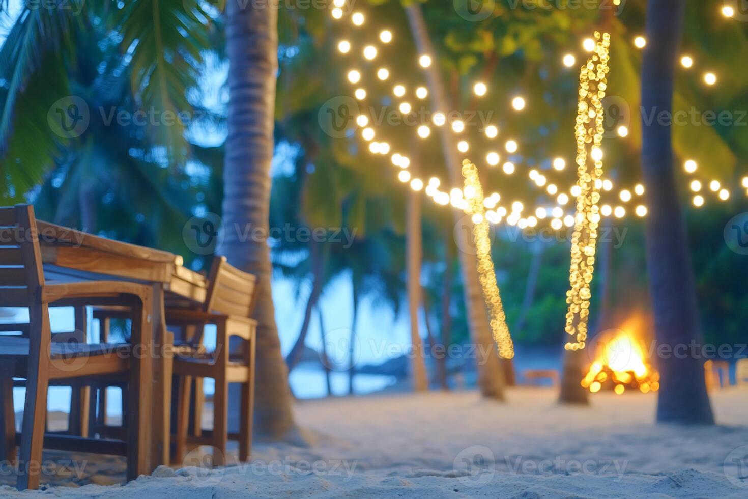 A table and chairs on the beach with string lights photo
