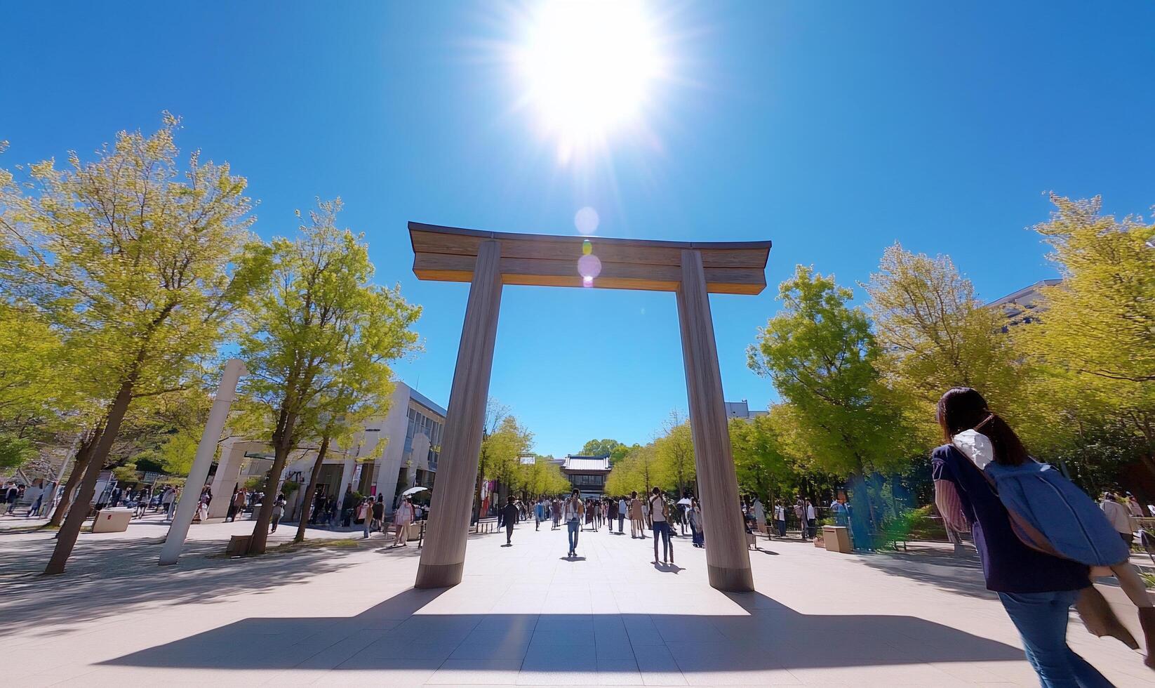 A sunny day at a torii gate surrounded by people and trees. photo
