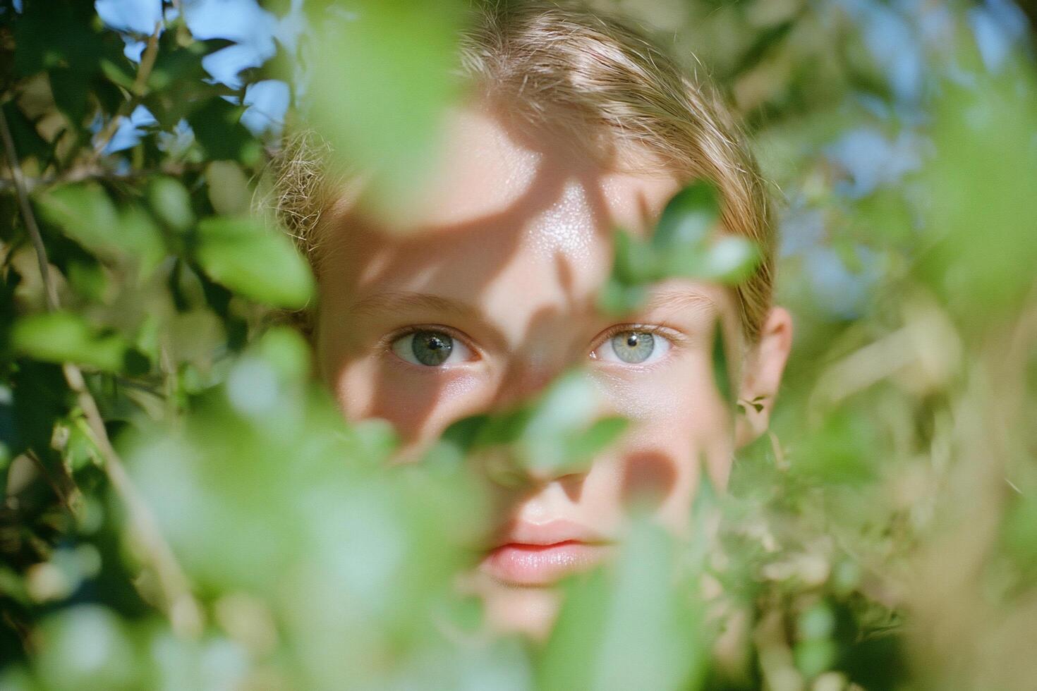 A close-up of a person's face partially obscured by foliage. photo