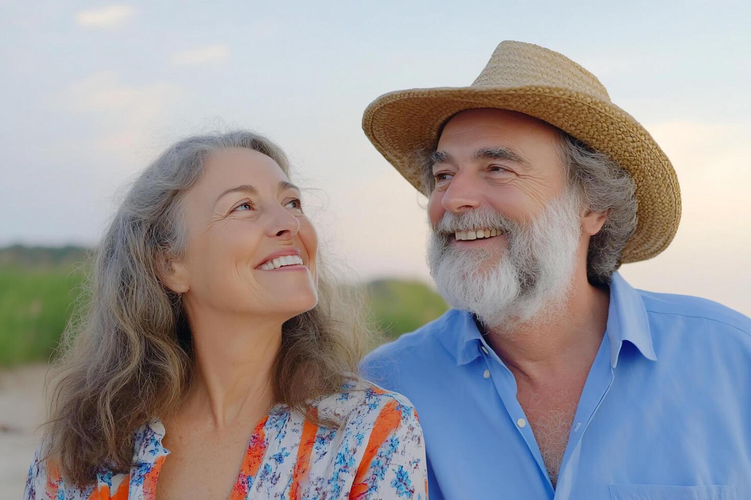 A joyful couple smiling at each other on a beach at sunset. photo