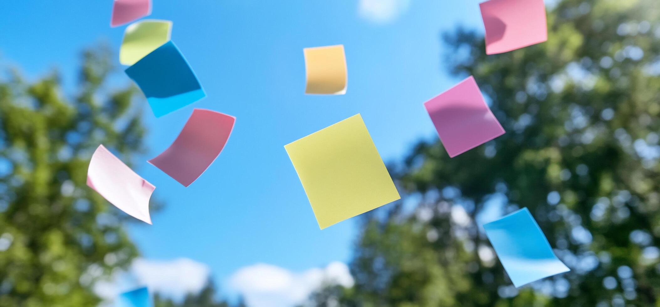 Colorful sticky notes floating against a blue sky and green trees. photo