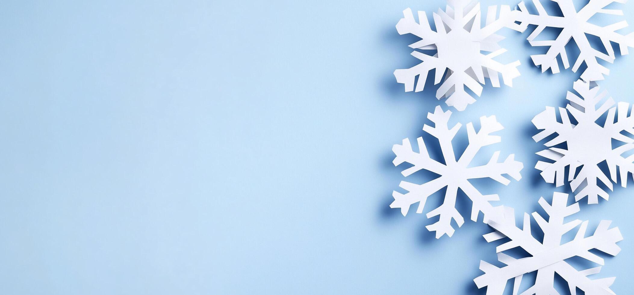 A collection of white paper snowflakes on a light blue background. photo