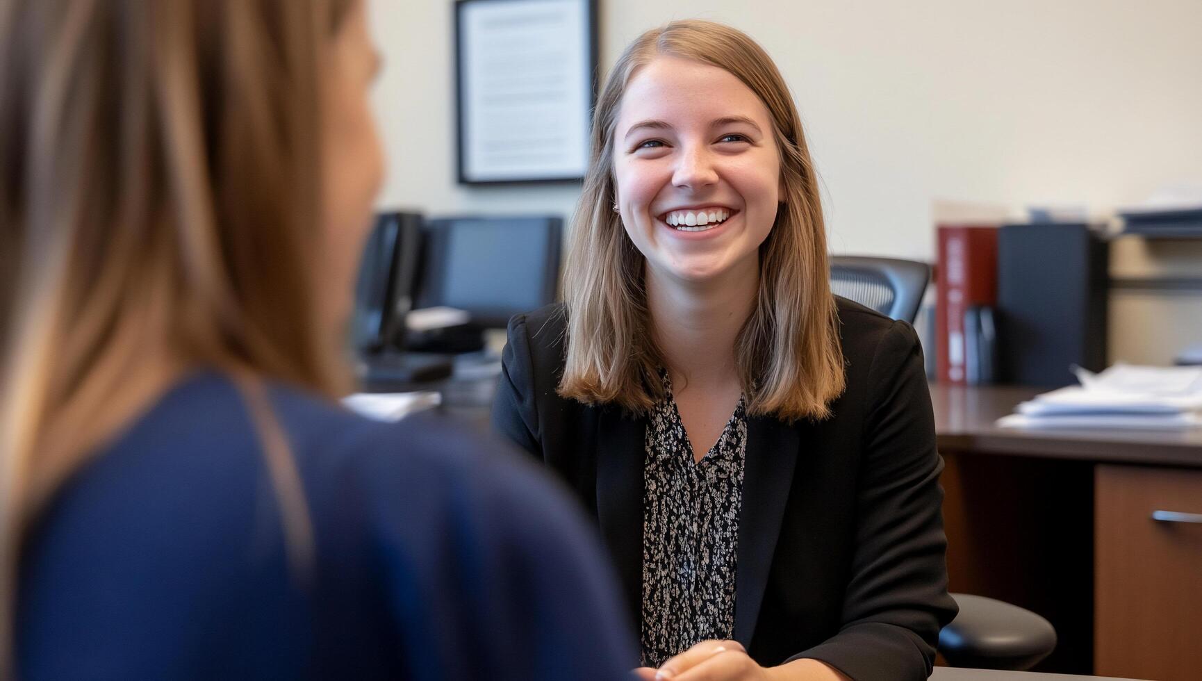 A smiling woman engages in conversation at a professional setting. photo