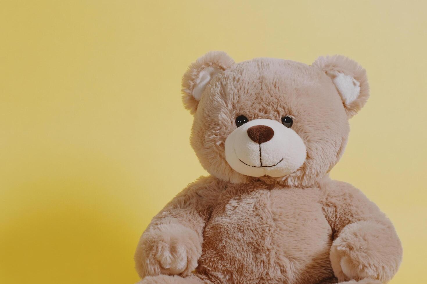 A plush teddy bear sits against a yellow background, exuding warmth. photo