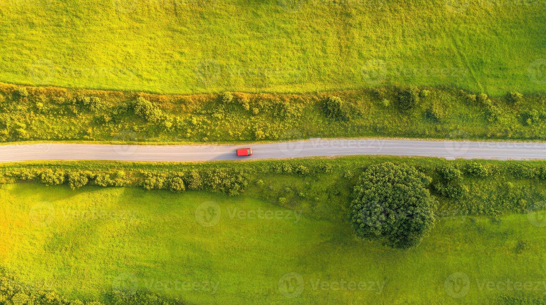 Aerial view of countryside road with red car in lush green fields photo