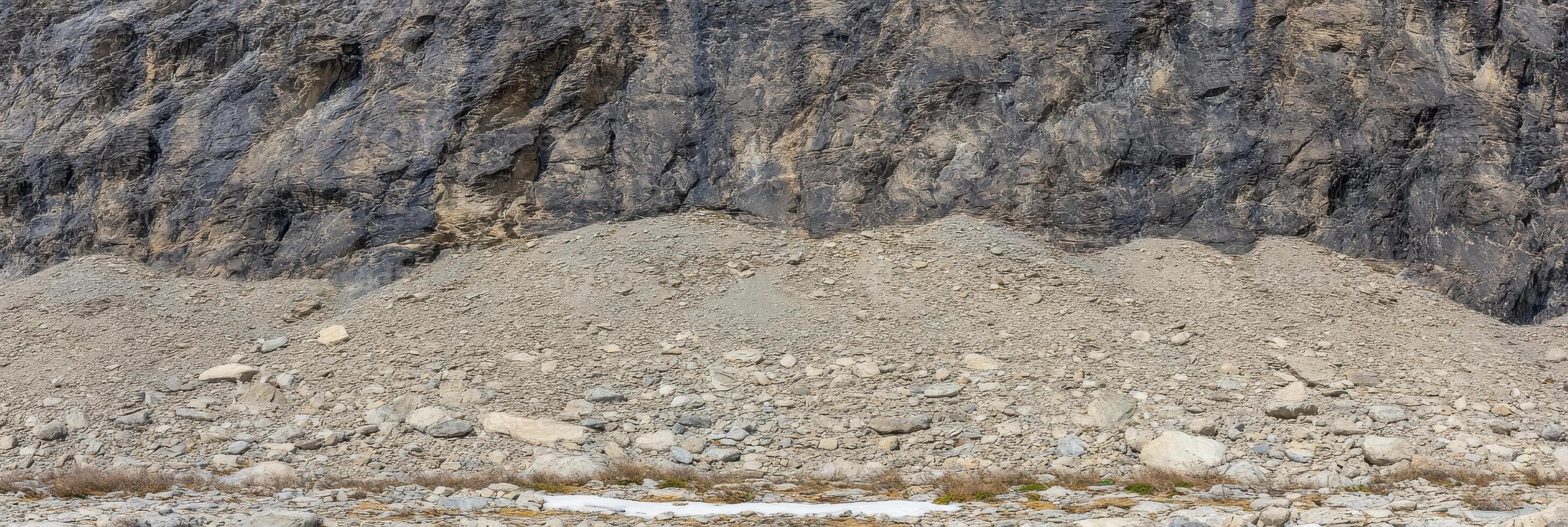 Rocky cliff face with loose debris and gravelly terrain in natural setting photo