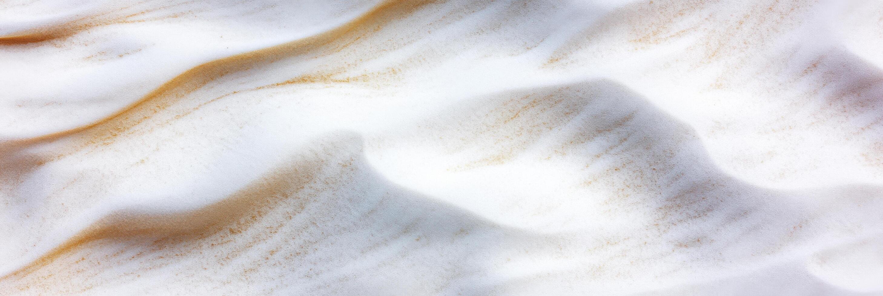 Aerial view of sand dunes with smooth patterns and gentle waves in desert landscape photo
