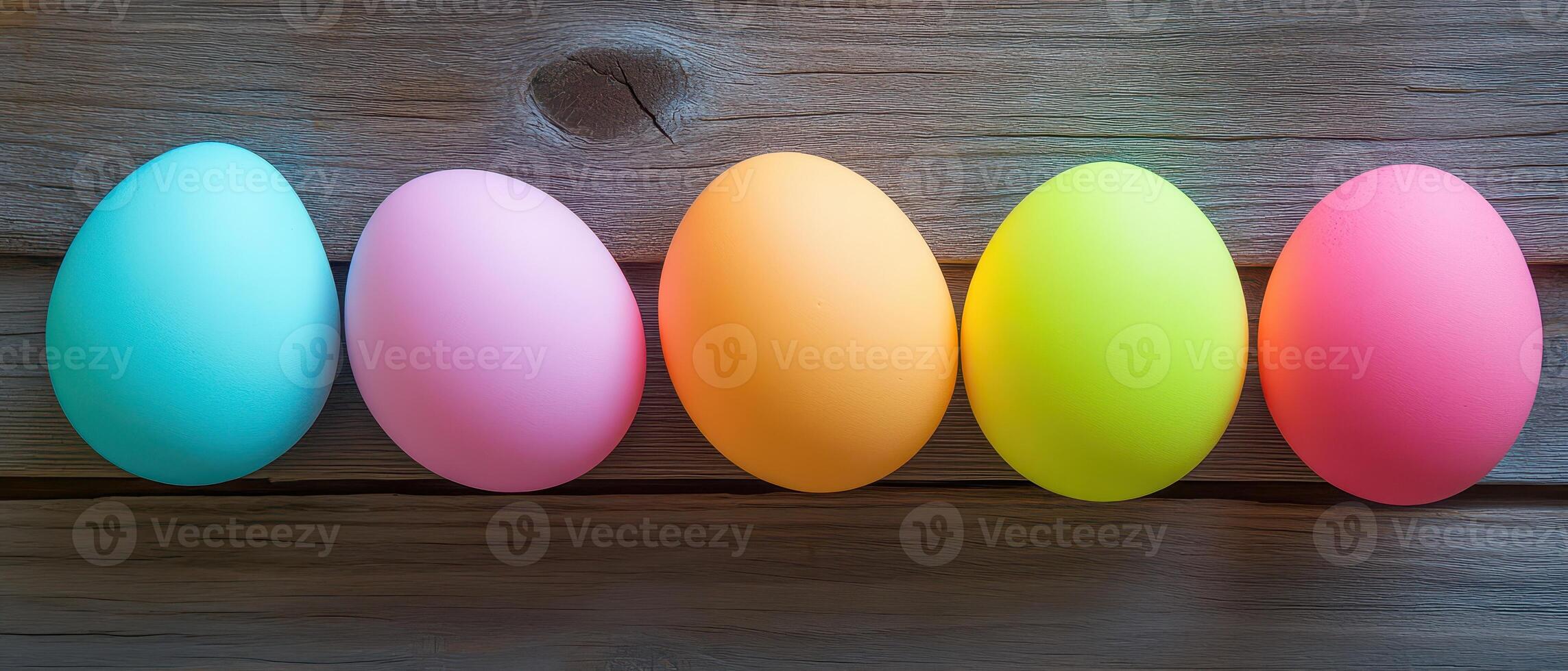 Five different colored eggs are lined up on a wooden surface photo