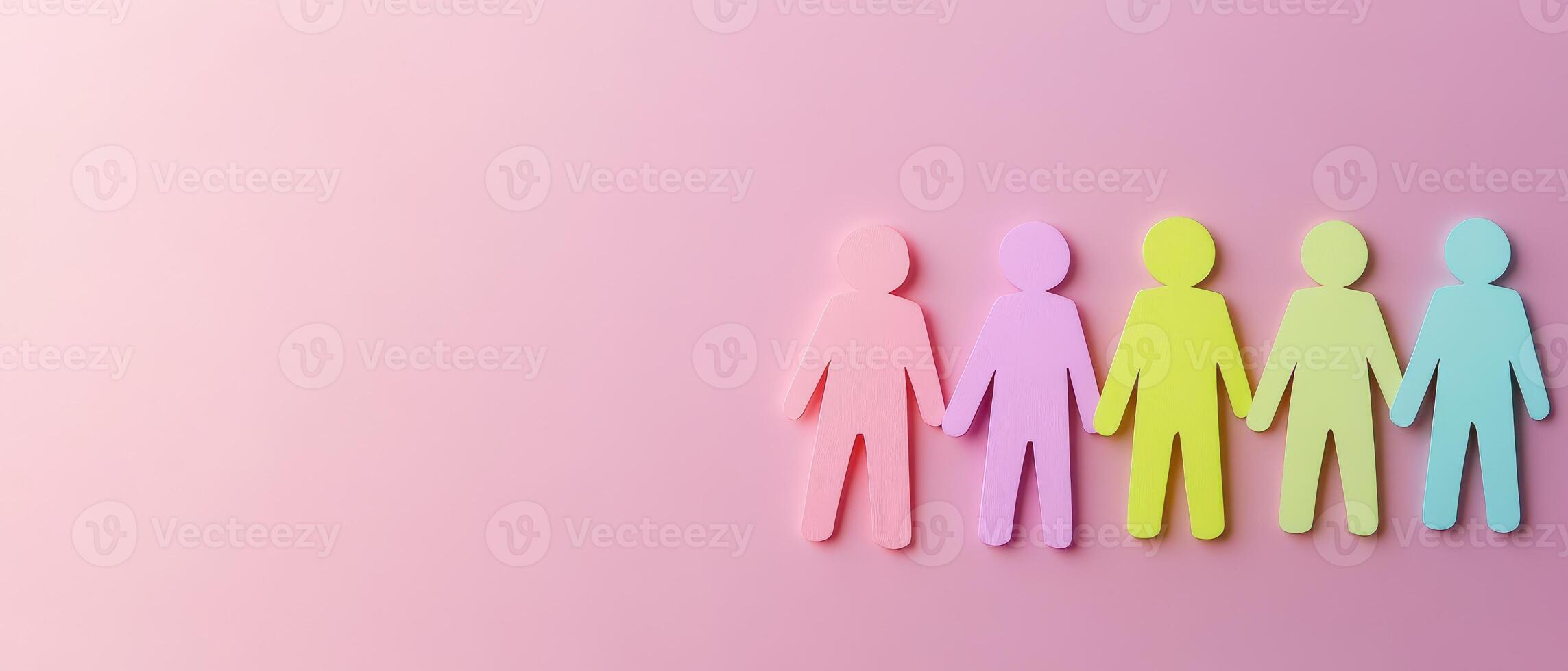 Colorful paper people standing in a line on a pink background photo