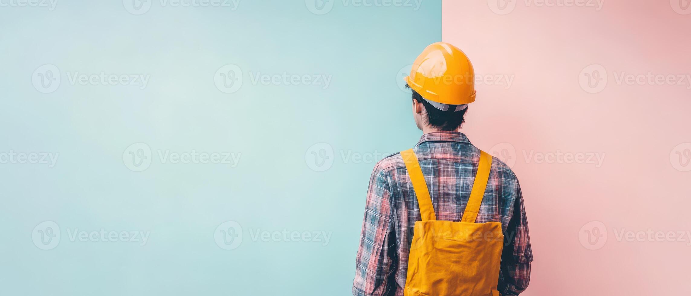 A man wearing a hard hat and a backpack standing in front of a wall photo
