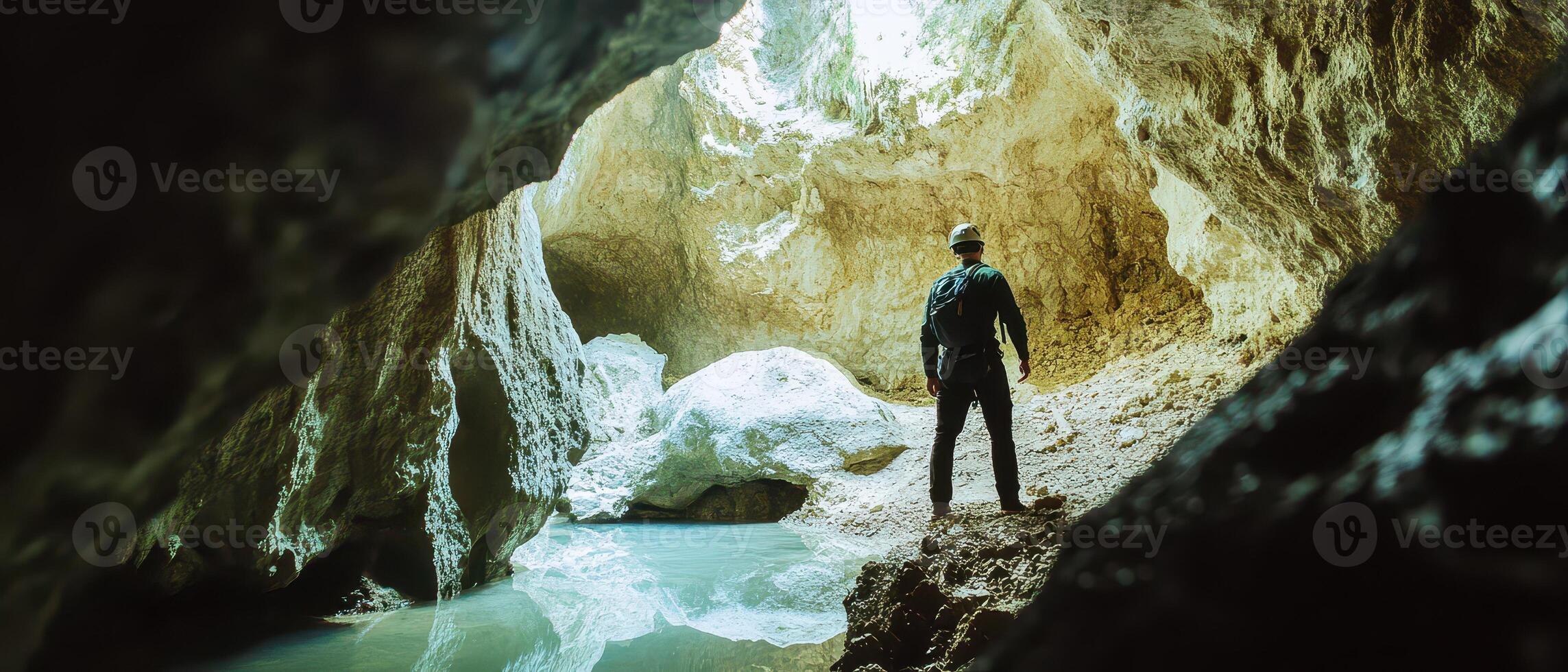 A man standing in a cave looking at the water photo