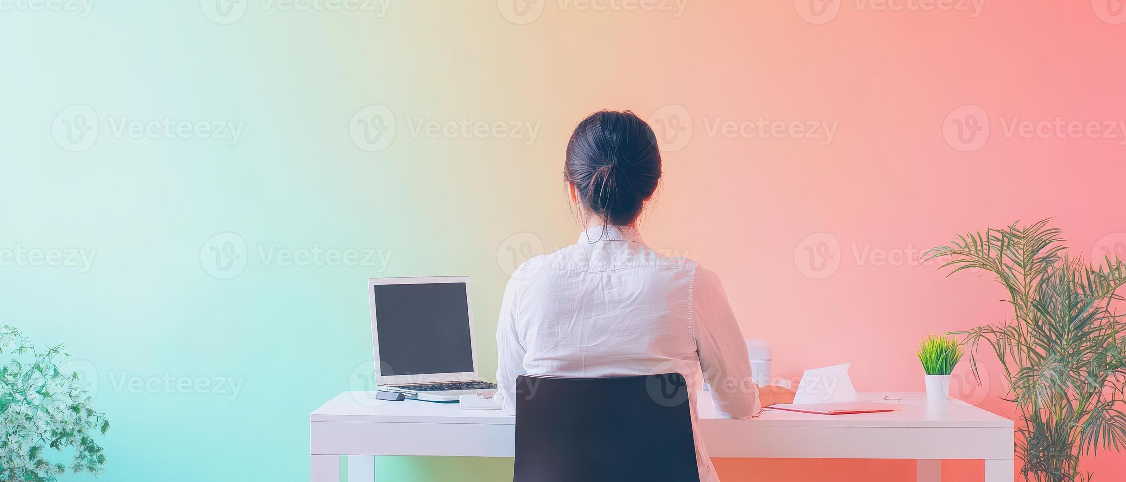 A woman sitting at a desk with a computer and a plant photo