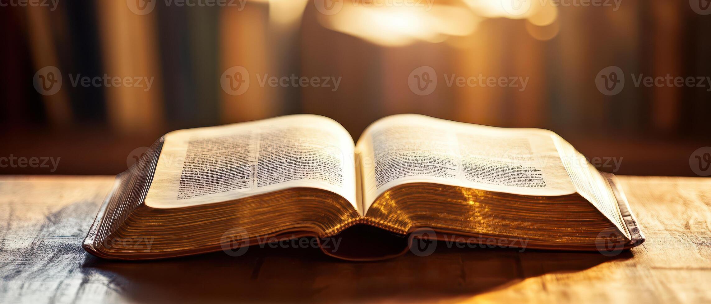Open book on wooden table with warm sunlight photo