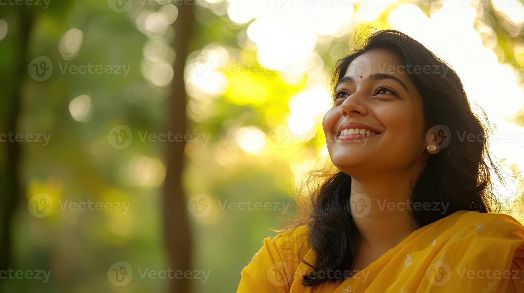 Beautiful Indian Woman Smiling and Looking Upward in Yellow Sari at Sunset photo