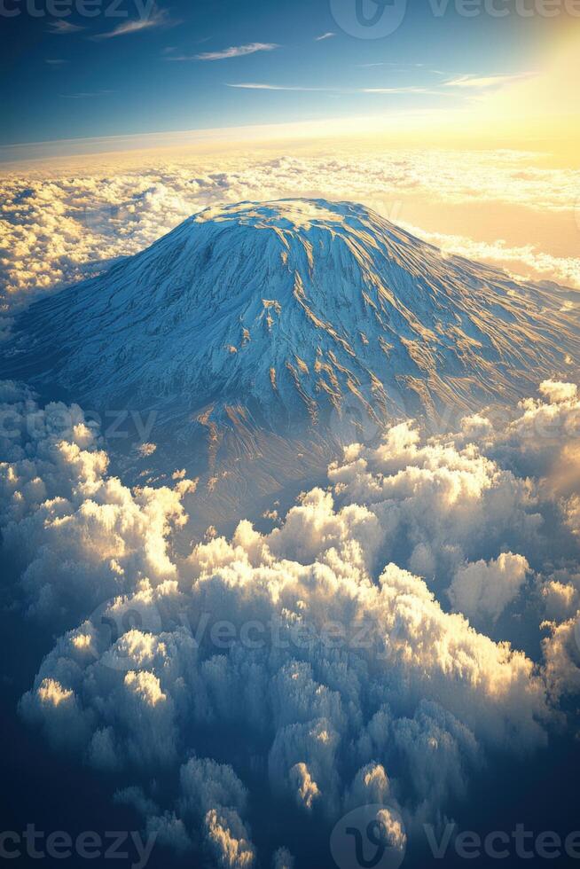 Snowy mountain rises above the clouds. The sun is shining brightly behind. Beautiful blue sky and cloudscape. Top view. photo