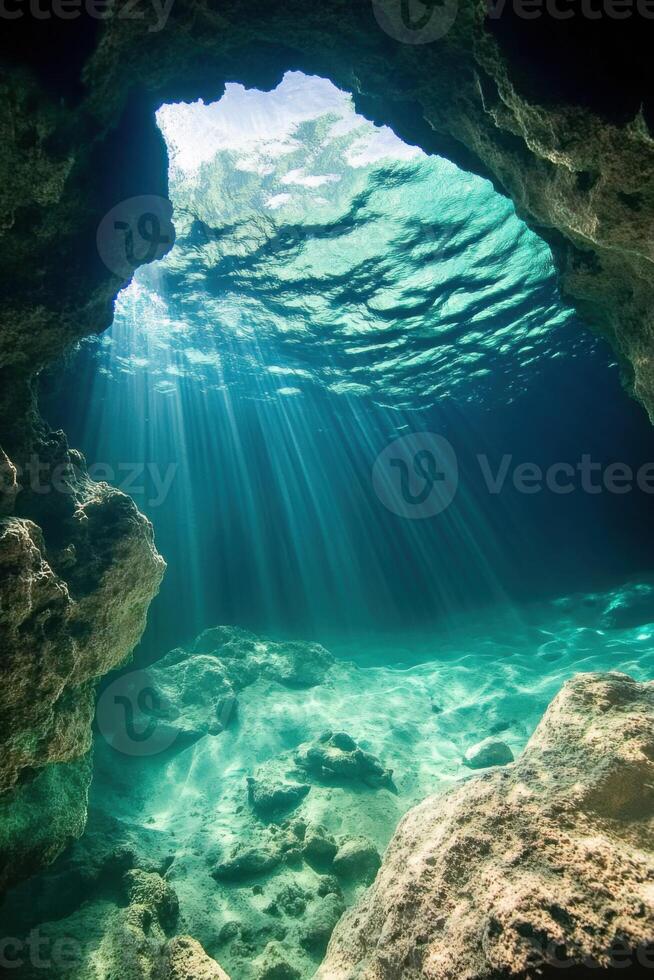Sun rays shine into sea cave. Light goes through clear water. Rocks surround the area. View of marine environment under water. photo