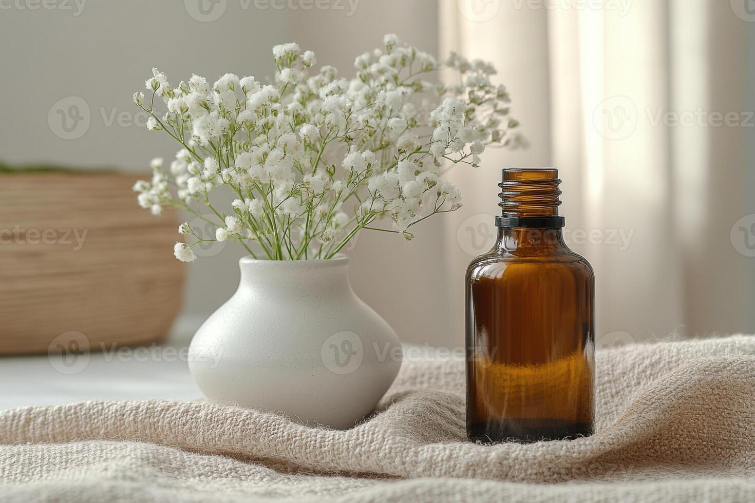 Small white flowers in a vase sit beside a brown bottle on a neutral cloth with sunlight and soft colors in a bright room photo