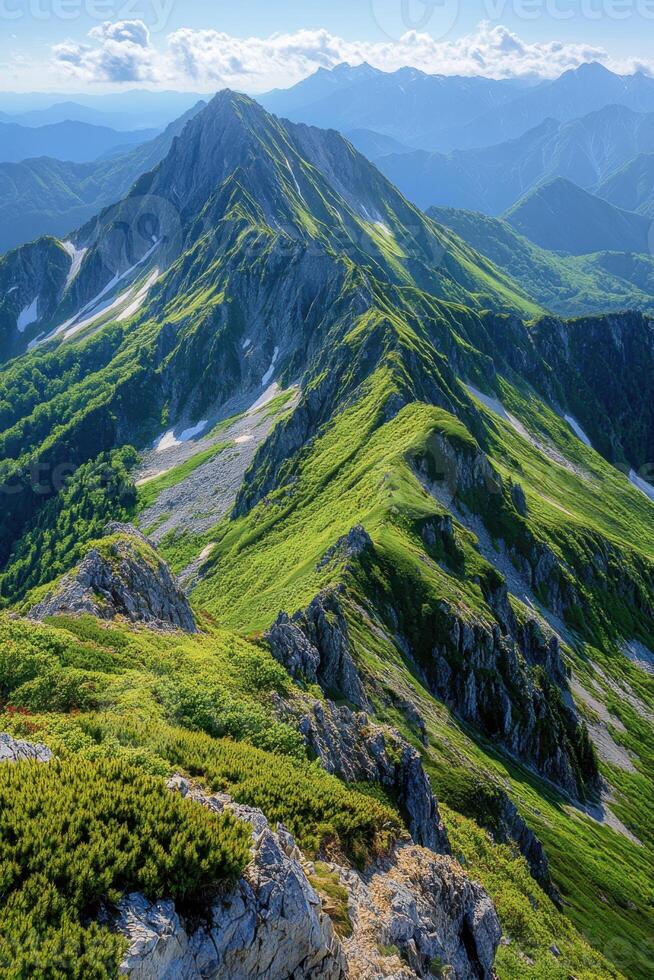 Scenic mountain ridge stretches toward distant peaks. Green grass and rock formations create a beautiful landscape with bright sky and wispy clouds. photo