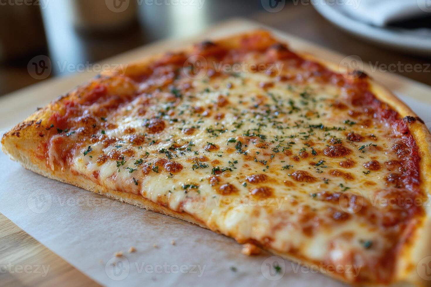 Single pizza slice with melted cheese and herbs on a wooden board and white paper. Pizza displays red sauce and a golden crust. photo