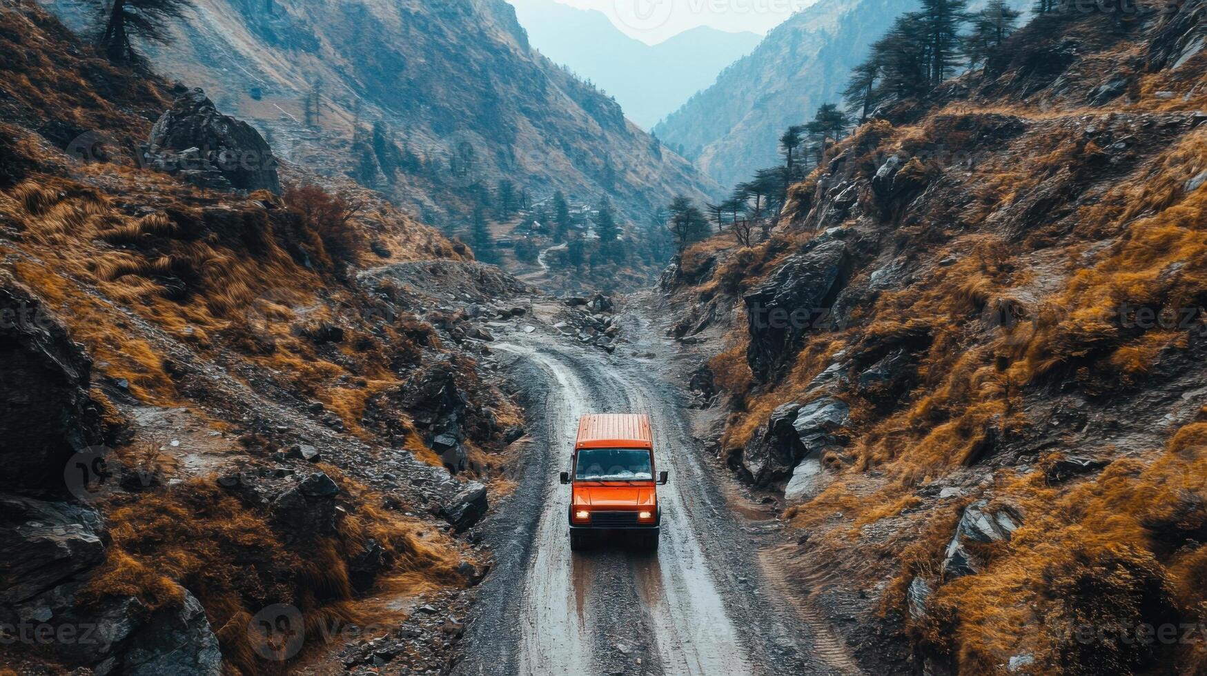 Orange vehicle drives on rough mountain road. Steep slopes with autumn colored vegetation line the path through tall hills. photo