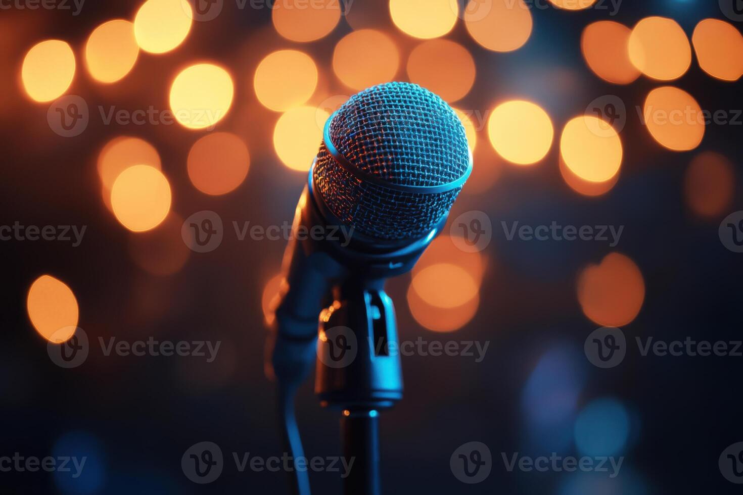 Microphone stands in front of blurry lights. Stage microphone ready to use. Studio equipment. Black background with warm orange glow. photo