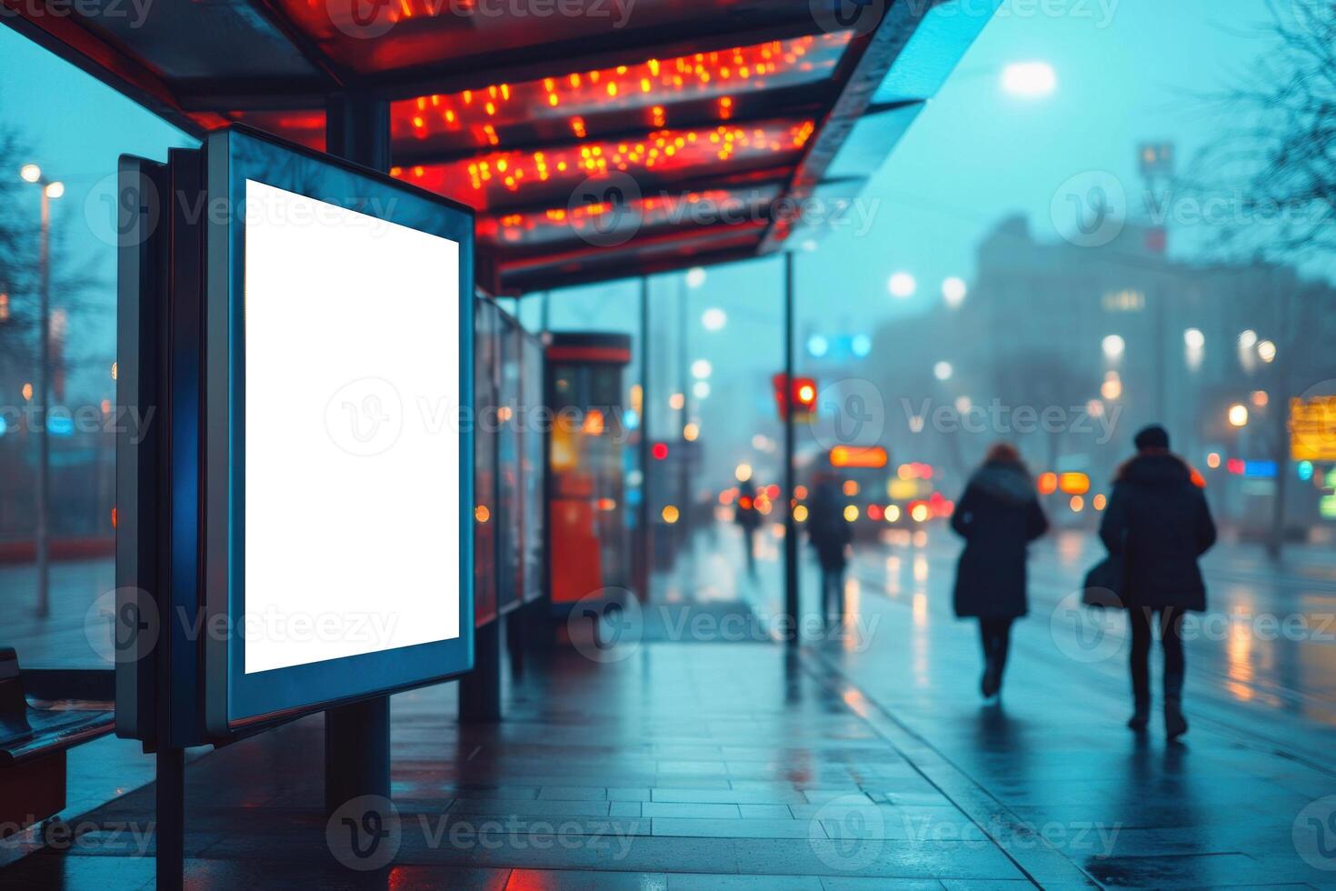 Blank billboard stands near bus stop. People walking on wet street in city at night. Colorful street lights shine through fog. photo